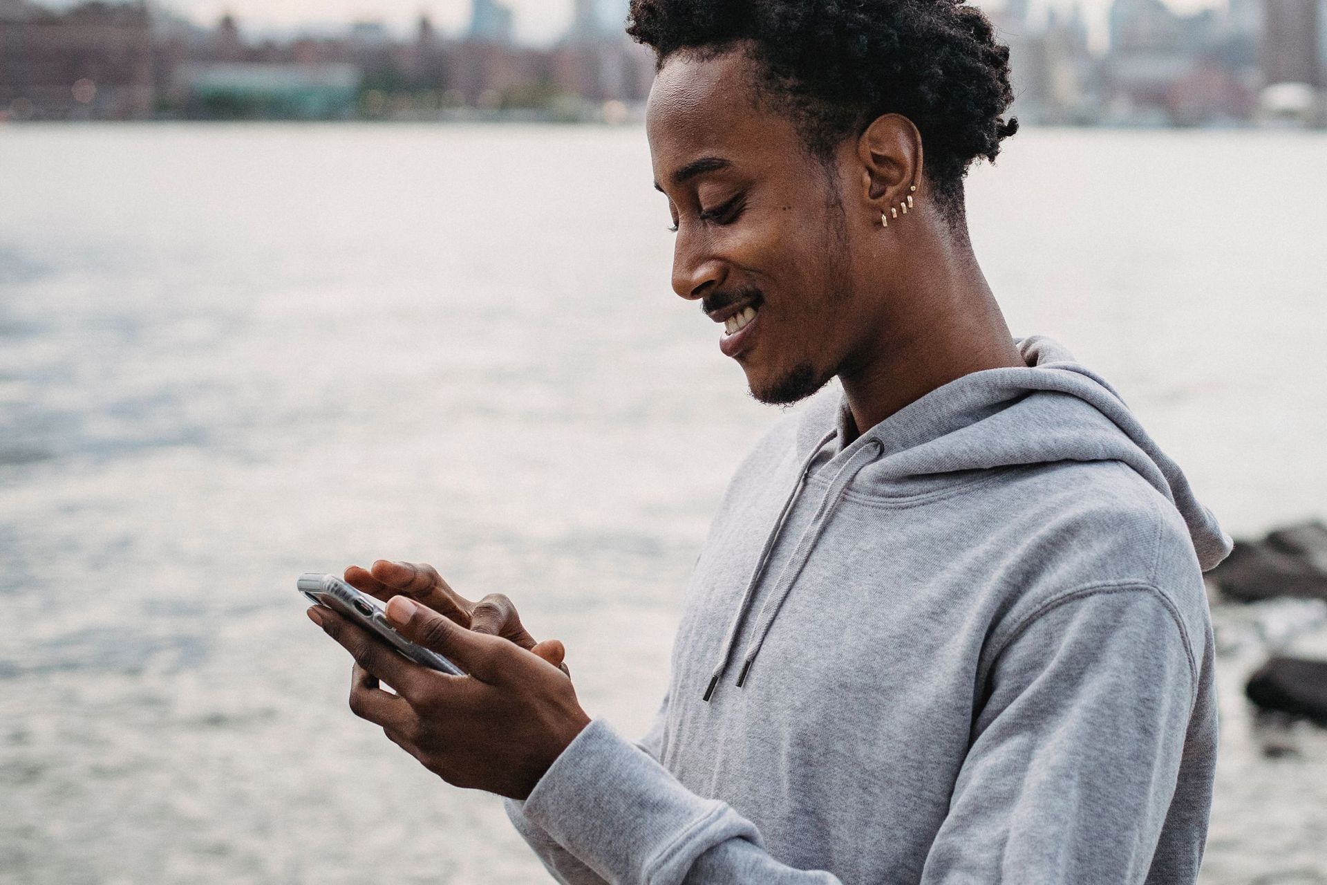 A young man smiling as he messages on his phone