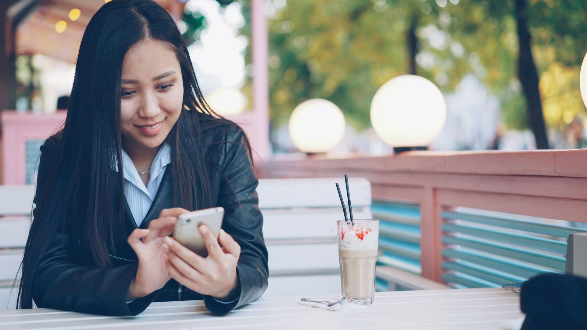 A young woman smiling at her phone in a café